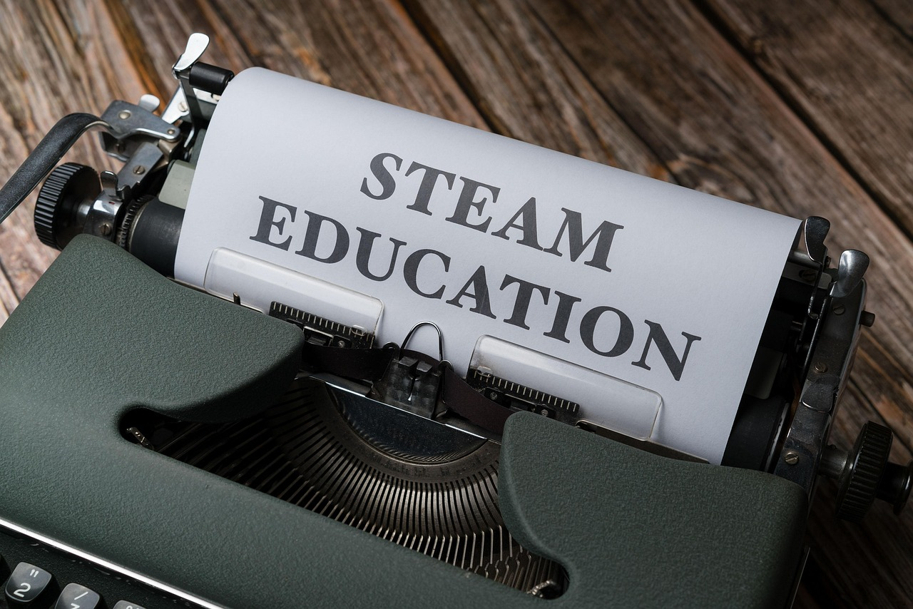 Close-up of an old vintage typewriter with the words 'STEAM EDUCATION' typed in large, bold letters on the paper.