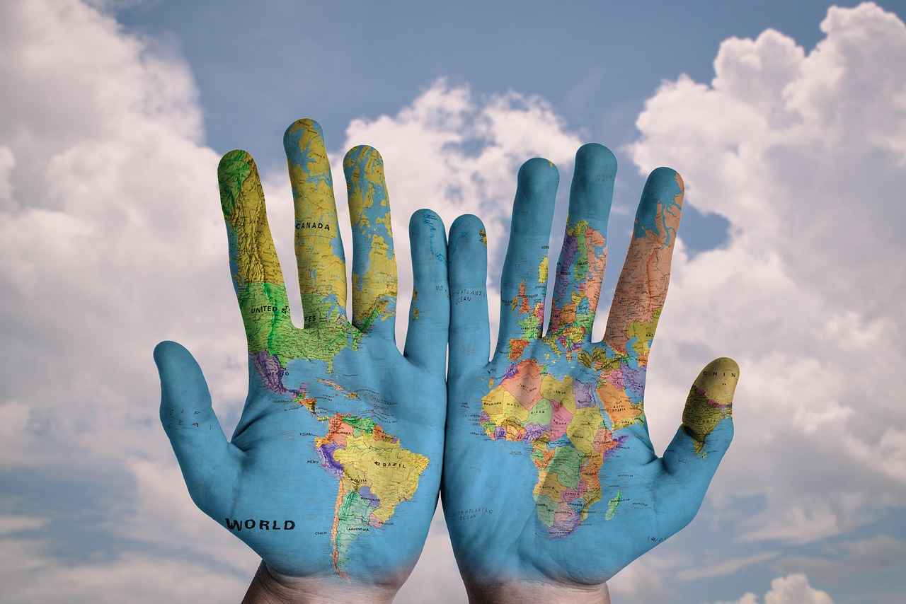 Two hands held up to the sky, painted with a detailed world map to represent global responsibility and environmental care.